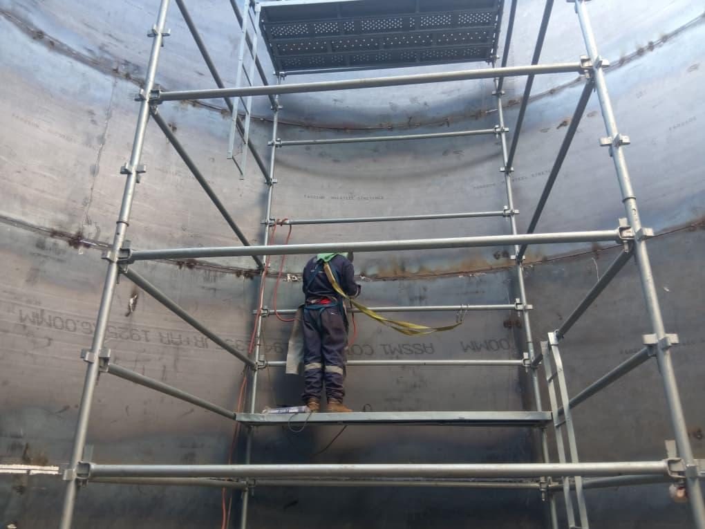 Welder on scaffolding inside a tank